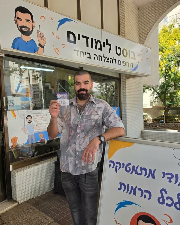 הבעלים של בוסט לימודים עומד בכניסה לעסק ומחזיק את כרטיס TapIL